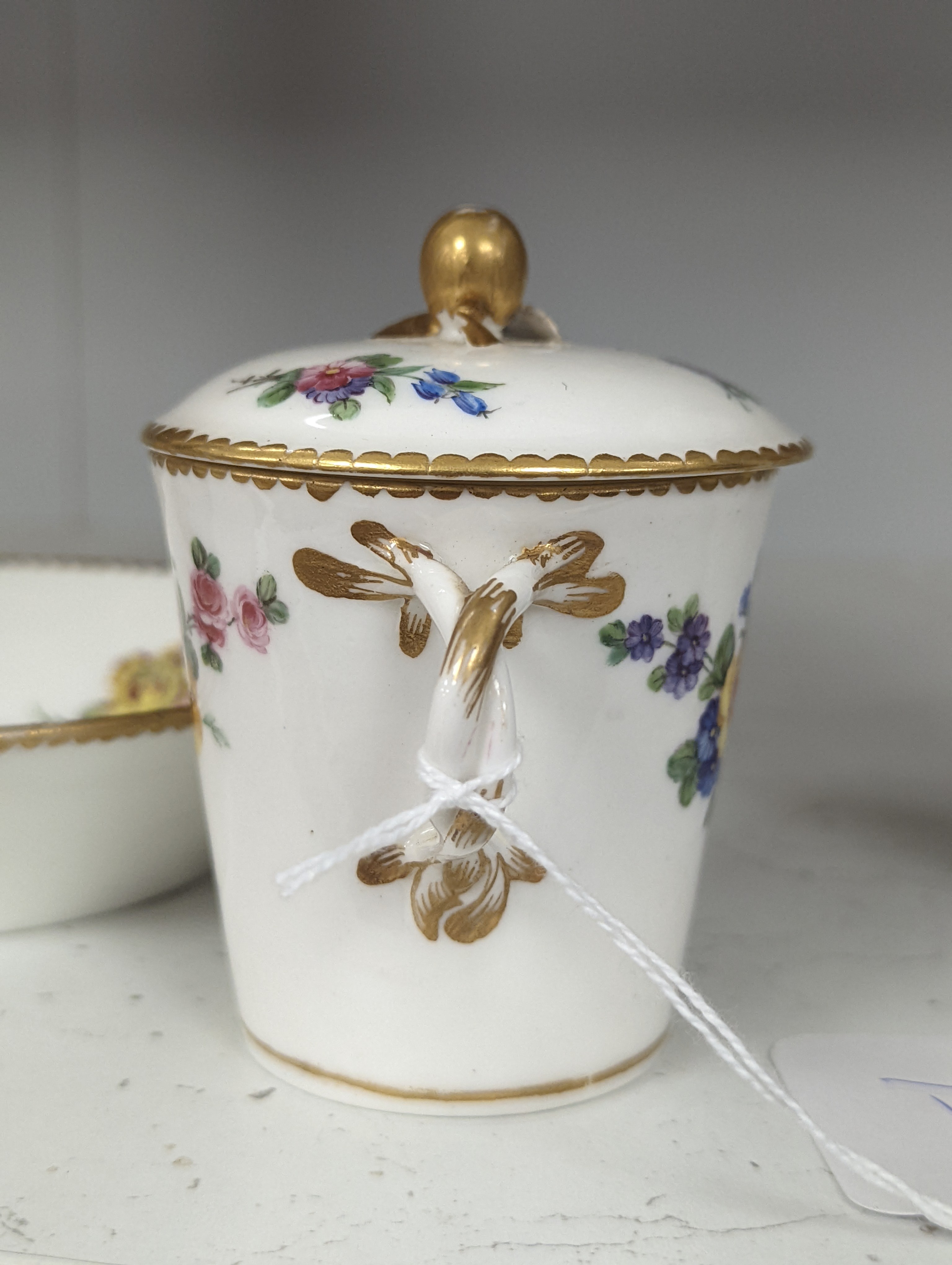 A Sevres tapering cup with entwined handle and cover and stand painted with flowers, date code for 1780, painters mark for Le Bel jnr., square incised marks, height 10.5cm